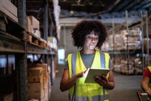 Woman in bright yellow reflective vest looking at a tablet. BMA Payroll helps small businesses gain transparency and cut costs.