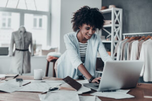 Blog 8 A small business owner confidently managing payroll on a laptop with financial documents in the background.